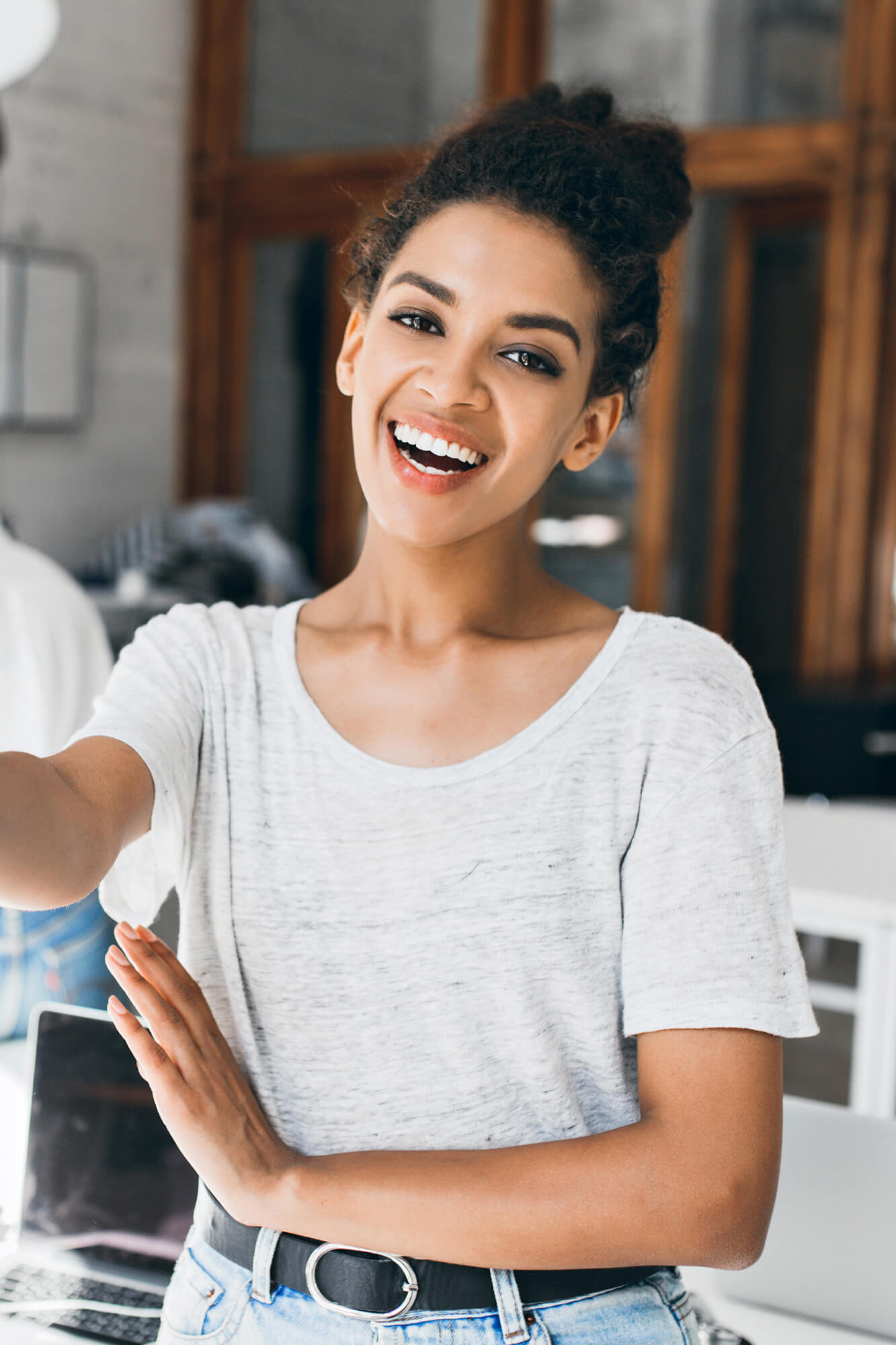 A woman smiling and holding her hand out to someone.